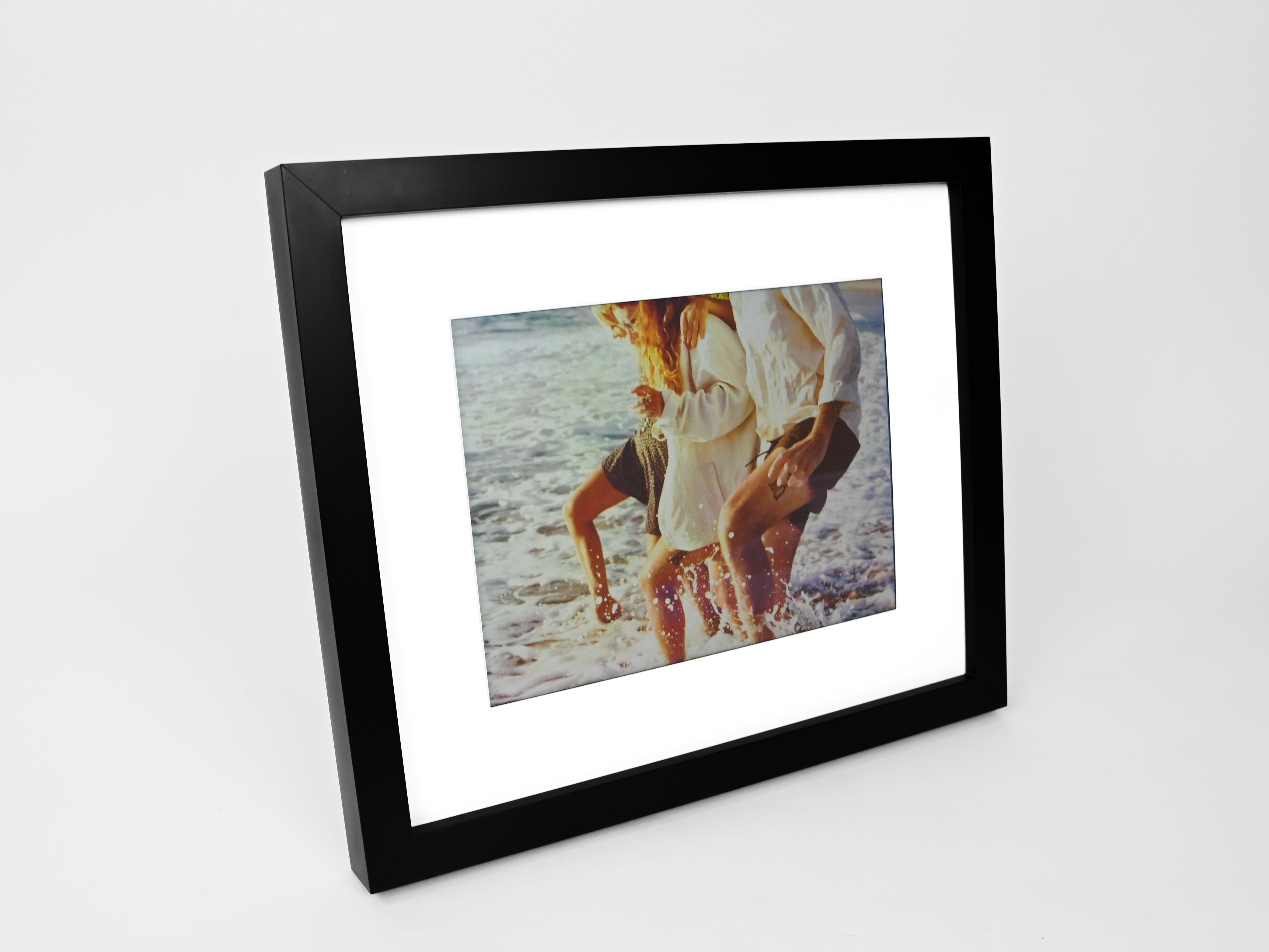 Framed photograph of a couple on a beach with a black frame. #black