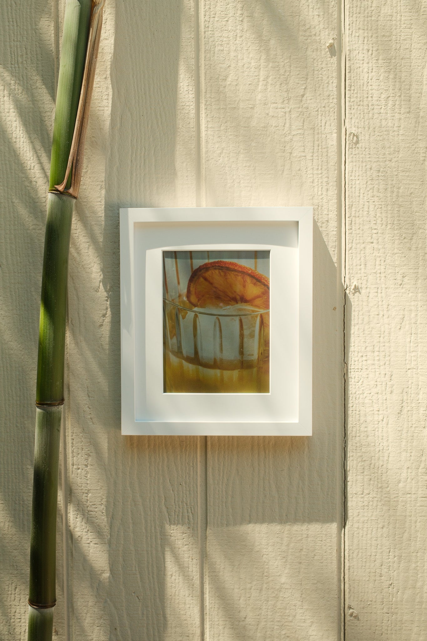 Framed artwork on a textured wall with a bamboo stick #white