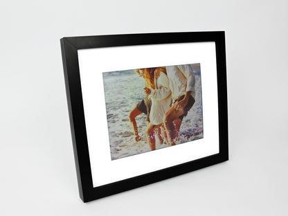 Framed photograph of a couple on a beach with a black frame. #black